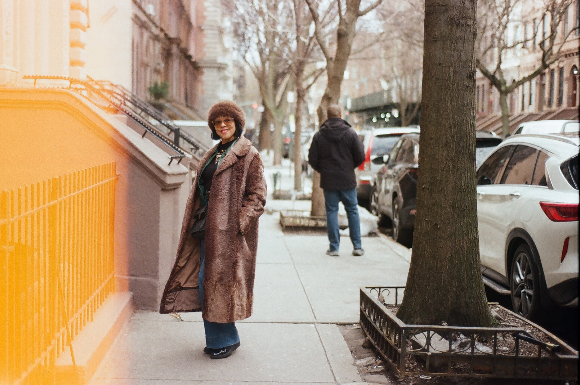 The curator of Mildred's Trove in a sable faux-fur coat and matching hat on a brownstone street in New York